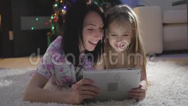 <strong>一家人的</strong>母亲和女儿在躺在地上数字平板电脑上<strong>的</strong>礼物。 圣诞节。